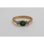 A 9ct gold ring set with an oval emerald and two diamonds (size M)