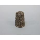 A white metal thimble with embossed floral and foliate decoration,