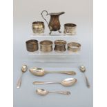 Six various hallmarked napkin rings, five silver spoons and a silver cream jug,
