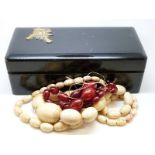 An ivory necklace and a cherry amber necklace in a wooden Chinese box