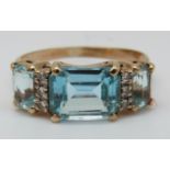 A 9ct gold ring set with three emerald cut topaz and diamonds (size O)
