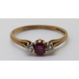 A 9ct gold ring set with an oval cut ruby and two diamonds (size M)