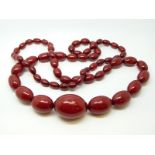 A cherry amber necklace of 63 graduated ovoid beads, the largest approximately 34x24mm, 83g,