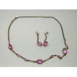 A silver necklace set with pink paste together with matching earrings