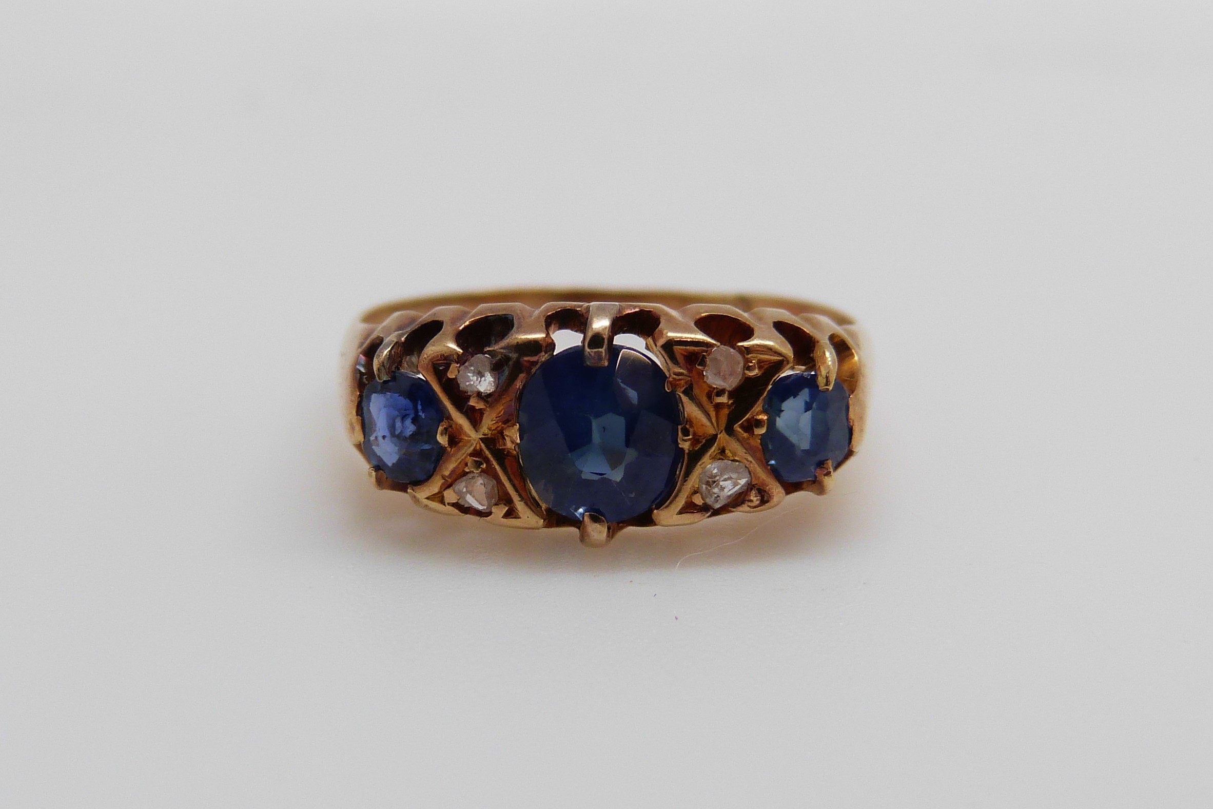 An 18ct gold ring set with three oval cut sapphires and four diamonds (size K/L)
