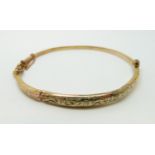 A 9ct gold bangle with engraved decoration, 4.