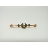 An Edwardian 9ct gold brooch set with seed pearls and a turquoise in a horseshoe design,
