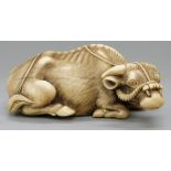 A signed Japanese Meiji period carved ivory netsuke of a recumbent oxen with harness,