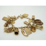 A 9ct gold charm bracelet with a large quantity of 9ct gold charms including cheque book,