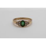A 9ct gold ring set with an oval cut emerald and three diamonds to each shoulder (size O)