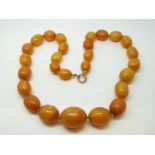 An amber necklace of 27 graduated ovoid egg yolk coloured beads, the largest approximately 24x19mm,