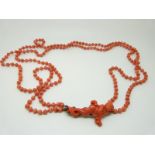 A Victorian two strand coral necklace with a carved coral clasp in the form of a cherub