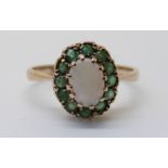 A 9ct gold ring set with an opal surrounded by emeralds (size K)