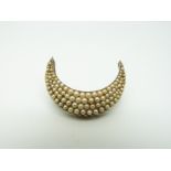 A Victorian brooch/ pendant in a crescent shape set with graduated seed pearls,