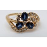 An 18ct gold ring set with three sapphires and diamonds in a floral setting (size R)