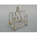 An Edward VII hallmarked silver four division toast rack raised on ball feet, London 1902,