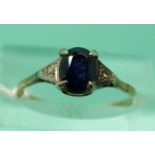 A 9ct gold ring set with an oval sapphire and two diamonds (size K)