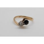 A 9ct gold ring set with a diamond and sapphire in a twist setting (size Q/R)