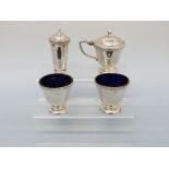 A George V Art Deco hallmarked silver four piece cruet set with blue glass liners,