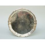 A George V hallmarked silver salver with shaped and reeded rim, raised on three paw feet,