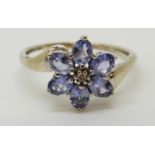 A 9ct white gold ring set with a diamond surrounded by tanzanite in a flower cluster (size M)