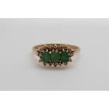 A 9ct gold ring set with three oval cut emeralds surrounded by diamonds (size N/O)