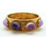 A late Victorian pinchbeck/ yellow metal hinged bangle set with eight large foiled amethyst