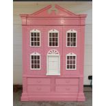 A pink painted child's wardrobe in the form of a doll's house,