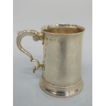 A Georgian hallmarked silver tankard of plain tapering form with C scroll handle,