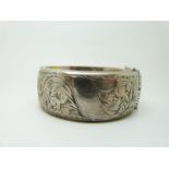 A hallmarked silver bangle with engraved foliate decoration