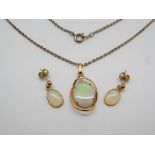 A silver pendant set with an oval opal and a pair of matching earrings