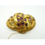 A Victorian yellow metal brooch of knotted design set with foiled oval cut almandine amethysts with