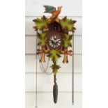 A mid to late 20thC cuckoo clock with painted vine leaf case decoration and pine comb weight