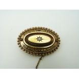 A Victorian 15ct gold brooch set with an old cut diamond in a star setting and foliate border,