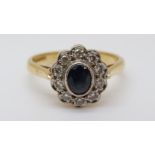 An 18ct gold ring set with a sapphire surrounded by diamonds in a cluster (size K)