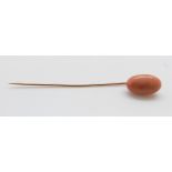 A stick pin set with a large coral cabochon, 6.5cm (cabochon 1.