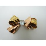 A 14k bi-coloured gold bow brooch set with an emerald cut aquamarine measuring approx 2.