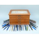 A pen collector's cabinet with four fitted drawers containing a collection of pens including