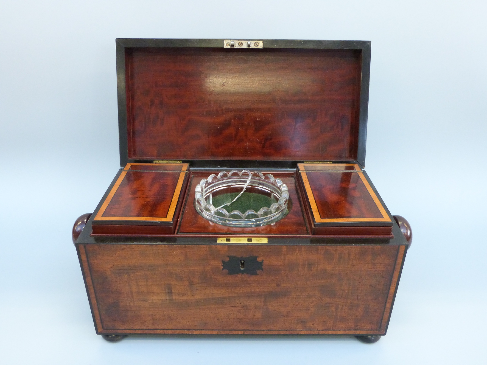 An early 19thC mahogany tea caddy of rectangular form with inlaid ebony detail, raised on bun feet,