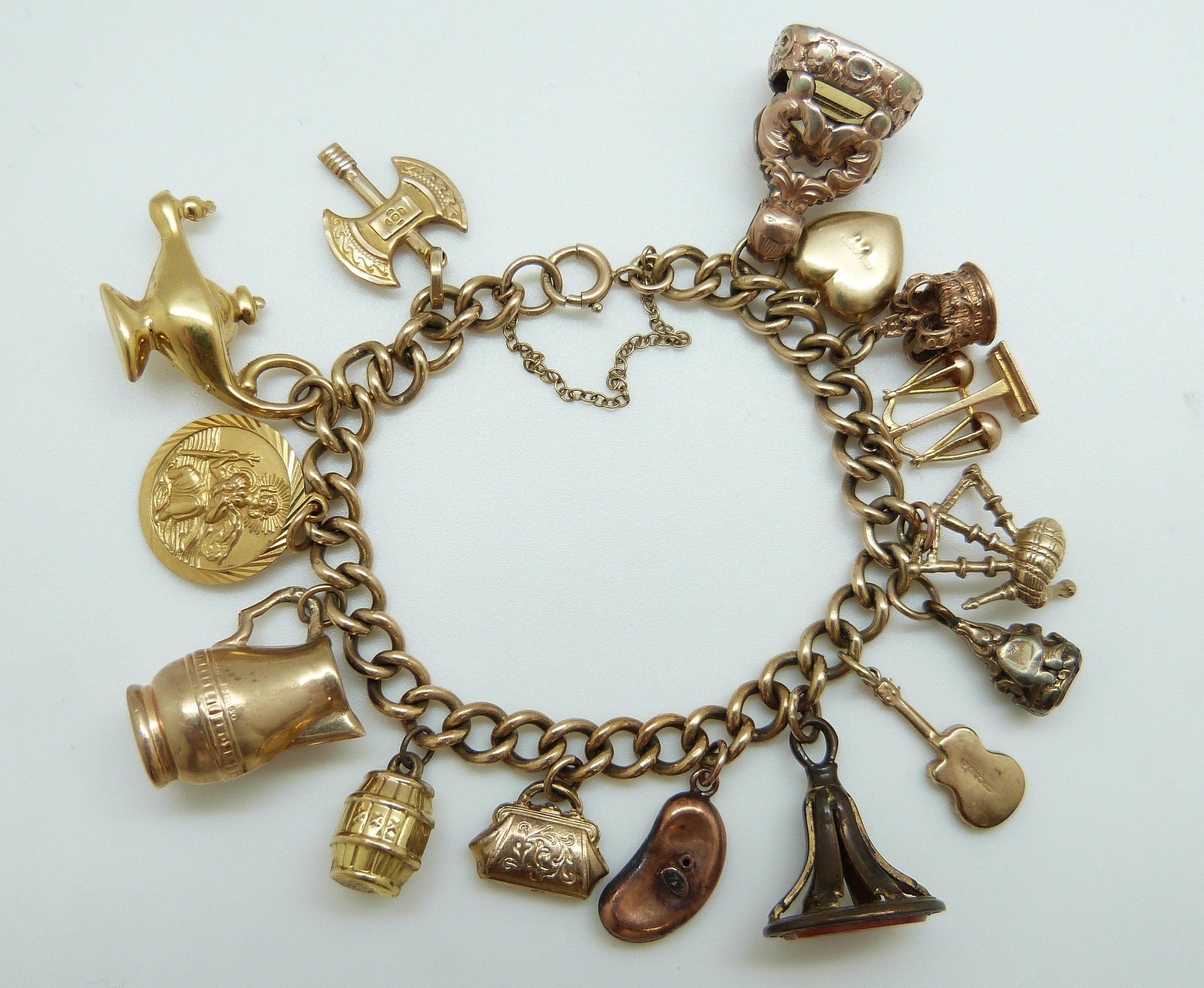 A 9ct gold charm bracelet with eleven 9ct gold charms including a crown, St Christopher, purse,