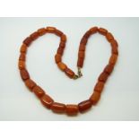 An amber necklace of 36 barrel shaped egg yolk coloured beads, the largest approximately 12x9mm,