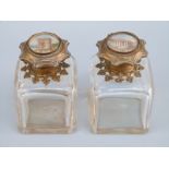 A pair of French scent bottles with ornate hinged tops inset with hand decorated Roman buildings,