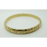 A 14k gold bangle with a textured surface,