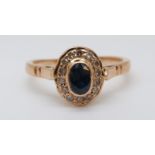 A yellow metal ring set with an oval sapphire surrounded by diamonds (size M)
