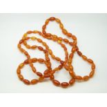 An amber necklace of 80 ovoid egg yolk coloured beads, each approximately 11x7mm, 22g, 100cm long.