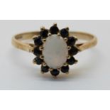 A 9ct white gold ring set with an opal surrounded by sapphires (size Q)