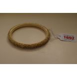 A Chinese carved ivory bangle, 9.5cm diameter.