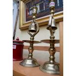 An unusual pair of brass candlesticks, the columns incorporating bells, 32.5cm high.