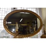 An old gilt wood and gesso framed oval wall mirror, 84 x 60cm.