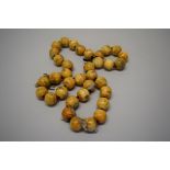 A Chinese carved ivory or bone bead necklace, of thirty-five near spherical beads,